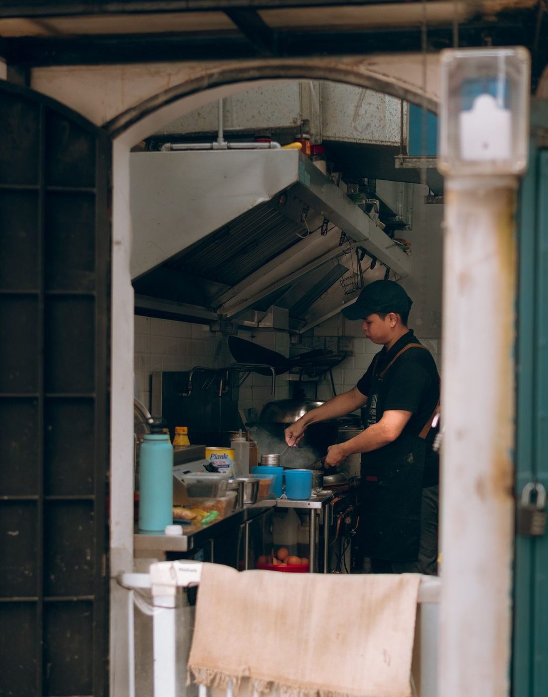 Nil cocinando en la cocina abierta del bistró, vista desde la puerta de la calle