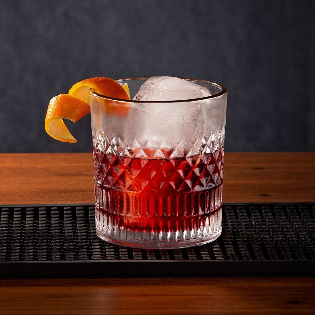 Vaso de vermut con hielo y piel de naranja sobre la barra